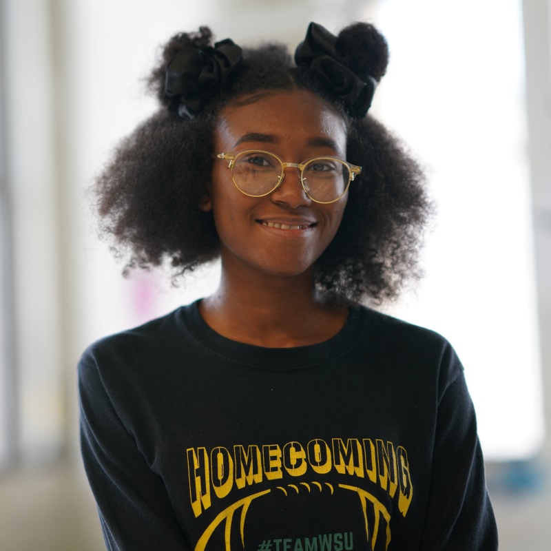 Student smiling with glasses and wayne state shirt on
