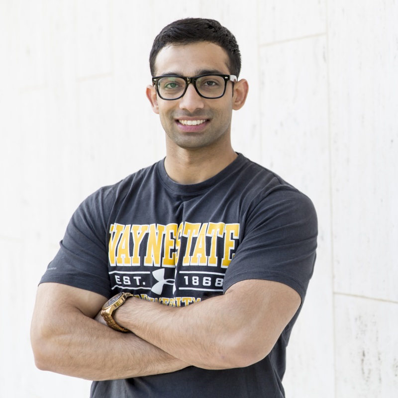 Student smiling with folded arms and Wayne State shirt on